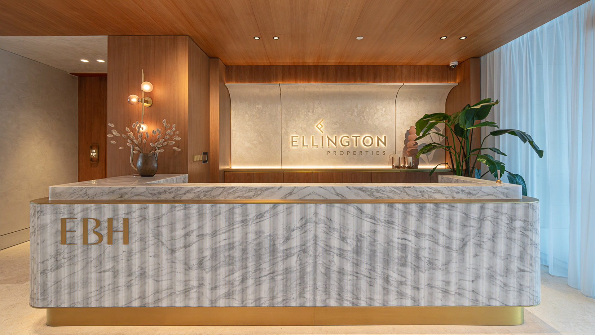 Ellington Beach House Palm Jumeirah reception area with rich materials of natural stone and wood finishes lighting design Nulty